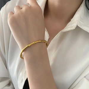 Bracelet jonc minimaliste en or au design de bambou mat porté au poignet par une femme
