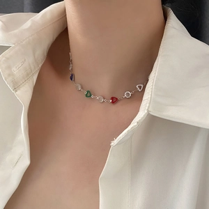 Colorful heart pendant necklace with silver chain and crystal accents worn on white shirt