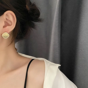 Square geometric gold-framed crystal earrings with subtle yellow texture on a model