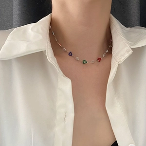 Colorful heart pendant necklace with transparent beads worn over a white shirt