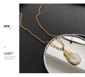 Gros plan du collier pendentif plume dorée avec nacre et incrustations de cristaux