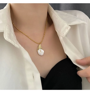 Détail du pendentif plume en nacre élégante avec chaîne à billes d'or et micro-zircons
