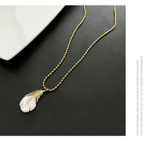 Détail du pendentif en forme de plume dorée avec nacre et incrustations de zircons