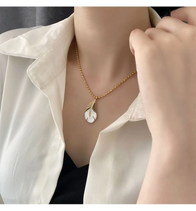 Détail du collier pendentif plume en nacre avec incrustation de zircon sur chaîne dorée
