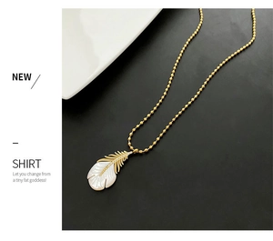 Détail du pendentif plume dorée avec nacre incrustée et cristaux de zircon brillants