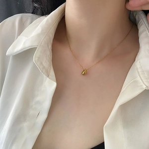 Elegant gold teardrop pendant necklace in titanium steel worn with white shirt