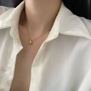 Polished gold teardrop pendant necklace in titanium steel on a white shirt model