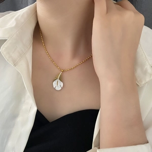 Élégant collier plume dorée avec incrustation nacre et zircons porté par un mannequin