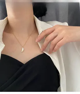 Gros plan d'un collier en acier titane doré avec pendentif triangulaire en nacre sur mannequin