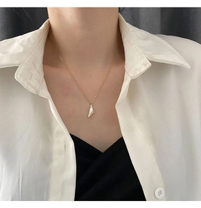Détail d'un pendentif triangle doré avec incrustation de nacre et zircons porté au cou