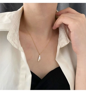 Détail d'un collier à pendentif géométrique doré avec incrustation blanche sur un mannequin