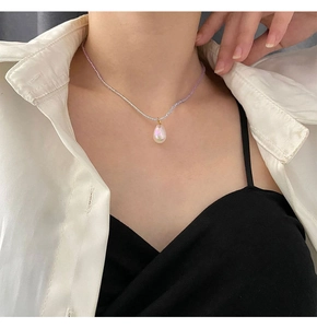Detail einer hellvioletten Perlenkette mit schillerndem Tropfenanhänger an einem Model
