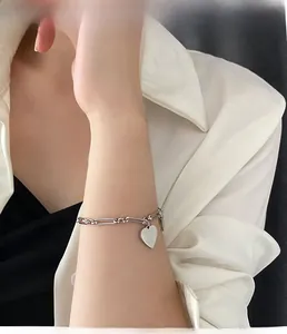 Dettaglio del bracciale con ciondolo a cuore in argento con catena indossato da una modella