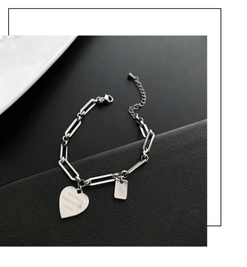 Dettaglio del bracciale in acciaio al titanio con fibbia OT e ciondolo a cuore inciso