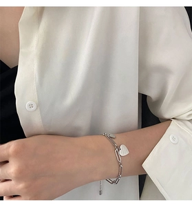 Dettaglio del ciondolo a cuore e charm rettangolare su bracciale a catena in titanio