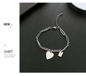 Dettaglio macro del bracciale a catena con ciondolo a cuore e targhetta incisa