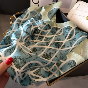 Détail d'un foulard en soie sarcelle avec motifs floraux sur un plateau doré
