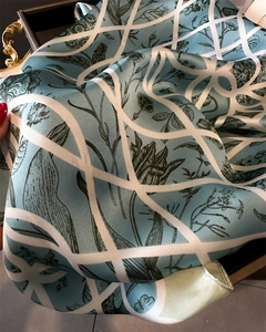 Détail d'un foulard en soie bleue avec imprimés floraux et lignes géométriques