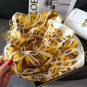 Détail de la texture d'un foulard en soie jaune avec motifs floraux et fini satiné