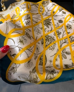 Détail d'un foulard en soie satinée avec imprimé fleuri et grille géométrique jaune