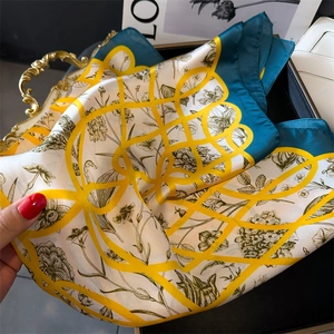 Détail d'un élégant foulard en satin aspect soie avec fleurs vintage et motifs géométriques