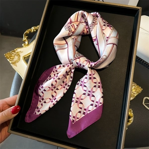 Elegant silk-like scarf featuring pink and purple chain prints tied in a bow on a tray