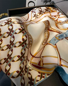 Close-up of elegant silk scarf with equestrian chain prints and gold buckle details