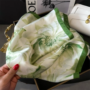 Detailed view of green floral print silk scarf with emerald border on vintage tray