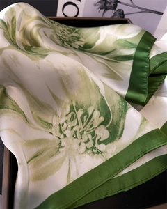 Detailed close-up of premium floral print silk scarf with emerald green hemmed edges