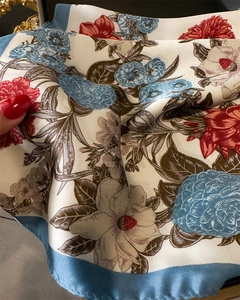 Close-up of printed silk-like scarf with large floral patterns and smooth blue border