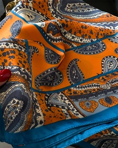 Detail of silk-like scarf with orange paisley print and blue hemmed edge texture