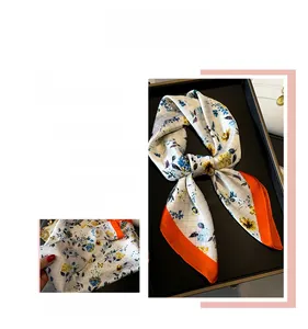 Detail of floral silk scarf with white grid pattern, yellow-blue blossoms and orange border