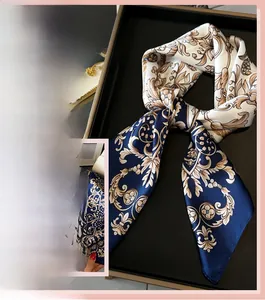 Detail of baroque silk scarf featuring golden vintage patterns on blue and cream satin fabric