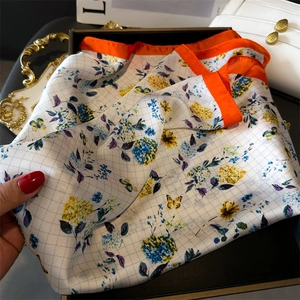 Detail of floral silk scarf with orange border, butterfly print and rhombus texture