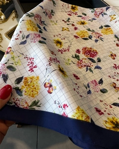 Detail of silk-like floral scarf with butterfly prints and elegant navy blue border
