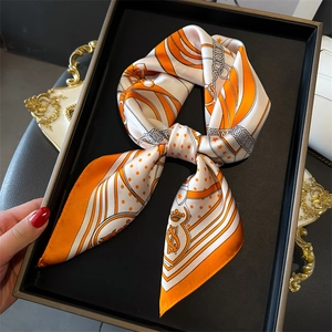 Classic orange and white silk scarf with chain horse-bit print on a black display tray