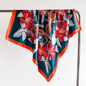 Detail of dark green floral silk scarf with hibiscus prints and orange hem stitching