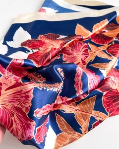 Detailed close-up of glossy floral silk scarf featuring vibrant red hibiscus patterns