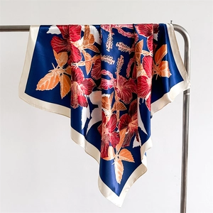 Detail of dark blue silk scarf featuring realistic red hibiscus prints and white borders