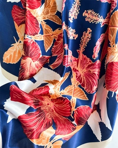 Detail of navy blue silk scarf featuring vibrant red hibiscus prints and a smooth satin finish