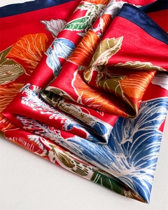 Detailed macro view of red satin floral scarf featuring hibiscus prints and navy hem