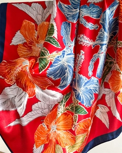 Detail of red floral satin scarf featuring hibiscus patterns and navy blue borders