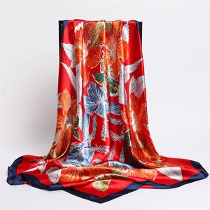 Detail of red floral satin scarf featuring tropical hibiscus patterns and navy blue edges