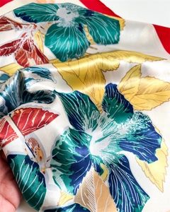 Close-up of vibrant tropical floral satin scarf with silky texture and fine red hem