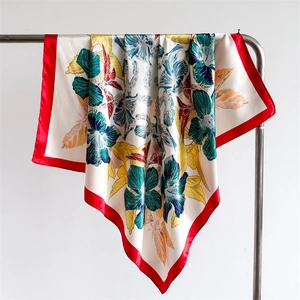 Detail of tropical floral print silk scarf with vibrant red borders on a hanger