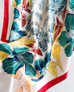 Detail of floral printed satin scarf with ivory base, red border and silky texture