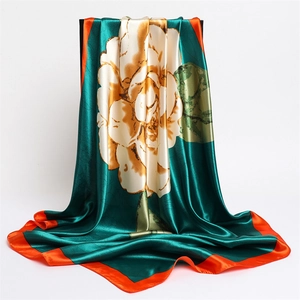 Detail of silk-satin scarf with deep green floral print and bright orange rolled edges