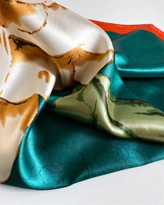 Detailed view of satin floral scarf with vibrant orange edges and elegant silk texture