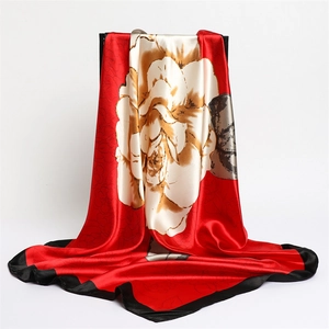 Satin silk scarf featuring large camellia prints and elegant black border on red base