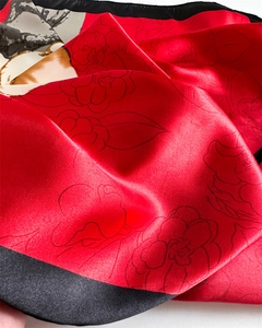Detailed close-up of smooth red satin scarf featuring elegant black floral line patterns